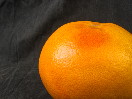 a large whole grapefruit on a black textile background