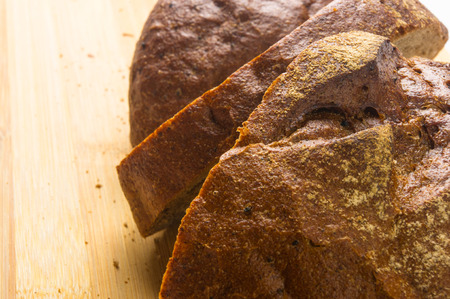 Sliced dark bread with crumbs on wood board
