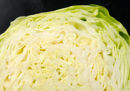 half head of Early cabbage on a wooden Board, on a dark background