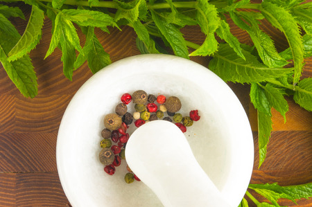 Fresh spearmint herb Mentha in the marble mortar with a pestle with spices, on a wooden backgroundの写真素材