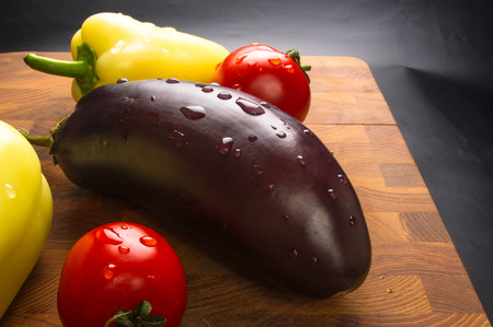 still life - yellow pepper, tomato and eggplant on wooden Boardの写真素材
