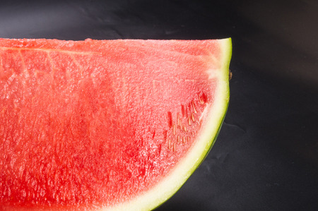a quarter of a ripe watermelon on a black background