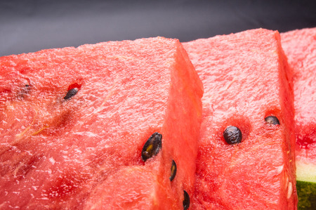 slices of ripe juicy watermelon in red plate on black backgroundの写真素材
