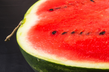 half of ripe watermelon on a black backgroundの写真素材