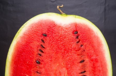 half of ripe watermelon on a black backgroundの写真素材