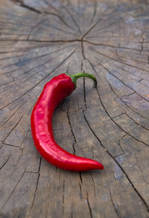 A pod of red hot chili peppers on the old worn wooden backgroundの写真素材