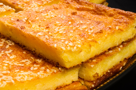 Slice of cheesecake with sesame seeds on a black background