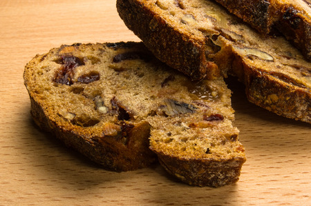 Slices of malt bread handmade with nuts, raisins and cranberries on wooden background