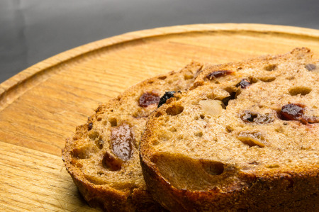 Slices of malt bread handmade with nuts, raisins and cranberries on wooden background