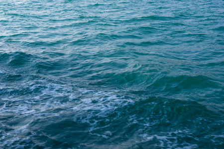 Wake jet with white foam in green sea waterの写真素材