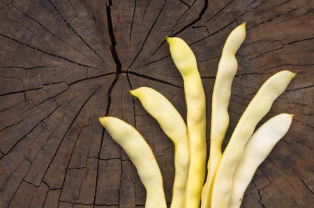large pods of white beans on old wooden background