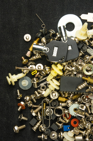 techno backgrounds - various bolts, screws, washers, nuts and other computer small fasteners on black fabricの写真素材