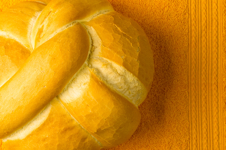 fresh braided loaf of white wheat bread on an yellow napkinの写真素材