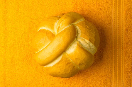 fresh braided loaf of white wheat bread on an yellow napkinの写真素材
