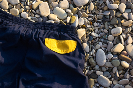 blue athletic shorts with yellow pockets on pebble beach, sunset