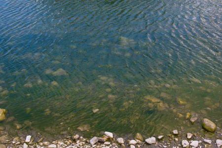 sea pebble beach with multicoloured stones, transparent waves with foam, on a warm summer dayの写真素材