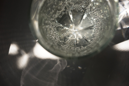 transparent faceted glass with bubbly water in the sun refracted lightの写真素材