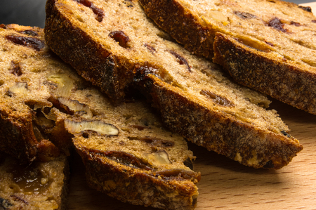 Slices of malt bread handmade with nuts, raisins and cranberries on wooden backgroundの写真素材