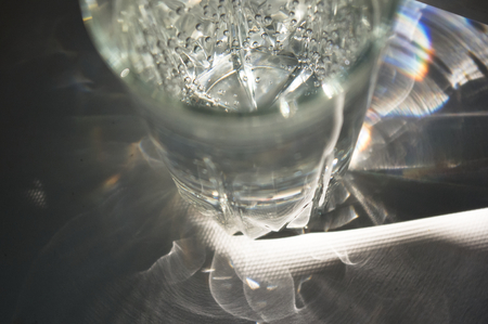 transparent faceted glass with bubbly water in the sun refracted lightの写真素材