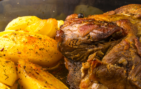 marinated pork with potatoes and spices, baked in the oven, on a black backgroundの写真素材