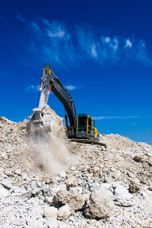 the excavator digging clay on blue sky backgroundの写真素材