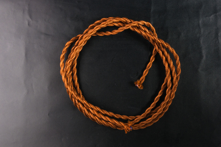 Electric cable in brown braid of fabric in retro style on black backgroundの写真素材