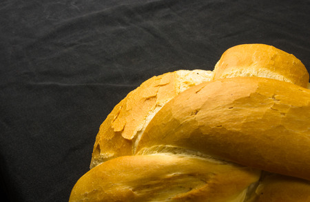 fresh braided loaf of white wheat bread on black background