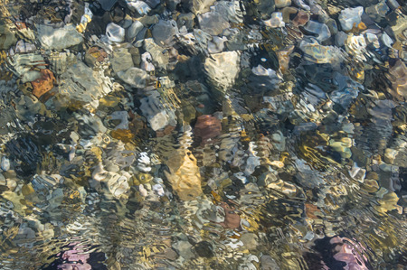 sea pebble beach with multicoloured stones, waves with foamの写真素材
