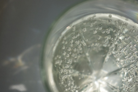transparent faceted glass with bubbly water in the sun refracted lightの写真素材