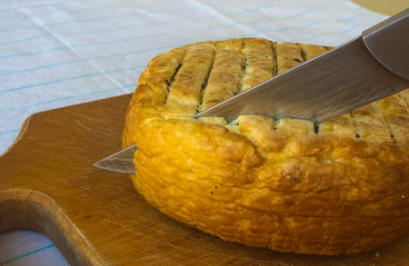 cut head of traditional Adygei cheese handmade with knife on wooden Boardの写真素材