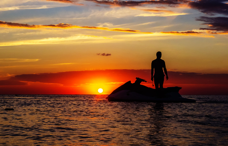 silhouette of a man on a jet ski in the sun on the sea sunset in summer eveningの写真素材