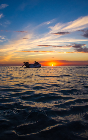 silhouette of a man on a jet ski in the sun on the sea sunset in summer eveningの写真素材