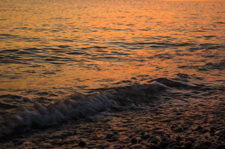Summer sea sunset on the pebble beach, the sun, waves and clouds, beautiful dramatic lighting