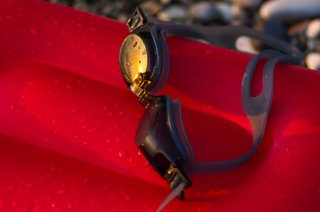 eyeglasses for swimming on a pebble beach in the sea waves, a warm summer day, close-up