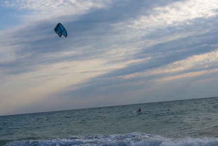 kitesurfer rides a kite-surf on waves of the sea in a small storm on a summer day