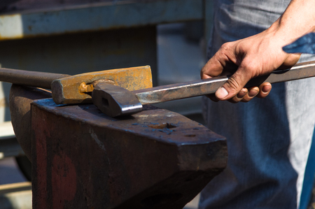 blacksmith performs the forging of hot glowing metal on the anvil, close-upの写真素材