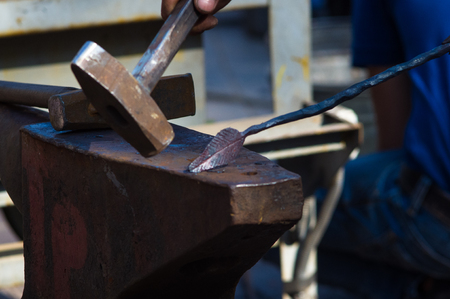 blacksmith performs the forging of hot glowing metal on the anvil, close-upの写真素材
