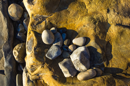 boulders and colorful pebbles on the beach on a warm summer dayの写真素材