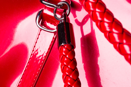 closeup of buckles, clasps, zippers, pockets, fasteners, fittings and seams on the red lacquer hand bagの写真素材