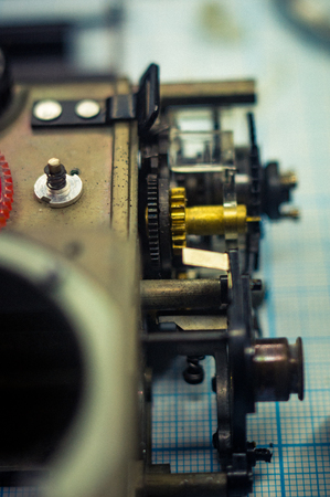 Parts are completely disassembled old retro film SLR camera on graph paper, close-up, toned