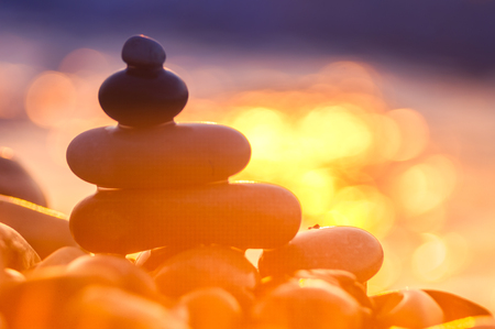 folded pyramid Zen pebble stones on the sea beach at sunsetの写真素材