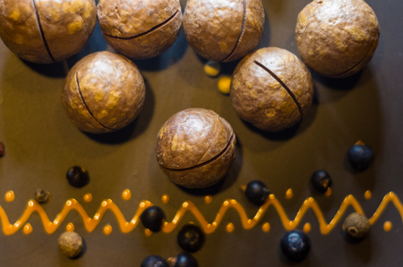 macadamia, Australian nut, juniper berries and allspice in a ceramic plate on a wooden table, close-upの写真素材