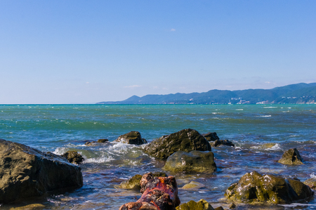 rocky sea shore with pebble beach, transparent waves with foam, on a warm summer dayの写真素材