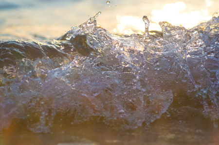 pebble stones on the sea beach on a warm summer day, the rolling waves of the blue sea with white foamの写真素材