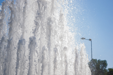 Fountain in city park on hot summer day, beautiful bright streams of sparkling water, drops and splashes.の写真素材