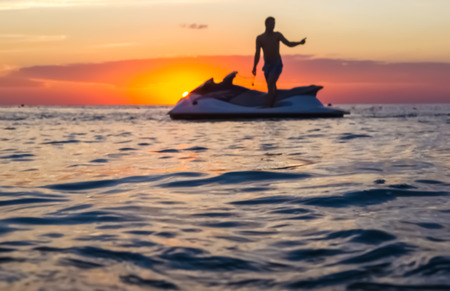 silhouette of a man on a jet ski in the sun on the sea sunset in summer evening