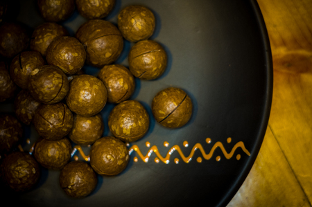 Macadamia, Australian nut in a ceramic plate on a wooden table, close-upの写真素材