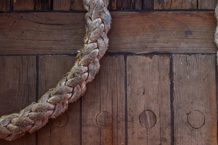 Old braided rope on the wooden deck of a sea boat, cleats, anchor mechanismsの写真素材