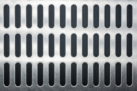 stainless steel grating with oblong holes on black background, close-upの写真素材