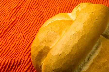 fresh braided loaf of white wheat bread on an orange napkinの写真素材